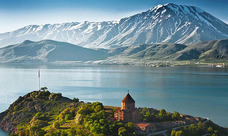 Sevanavank monastery on a hill above Lake Sevan, with snow-capped mountains behind